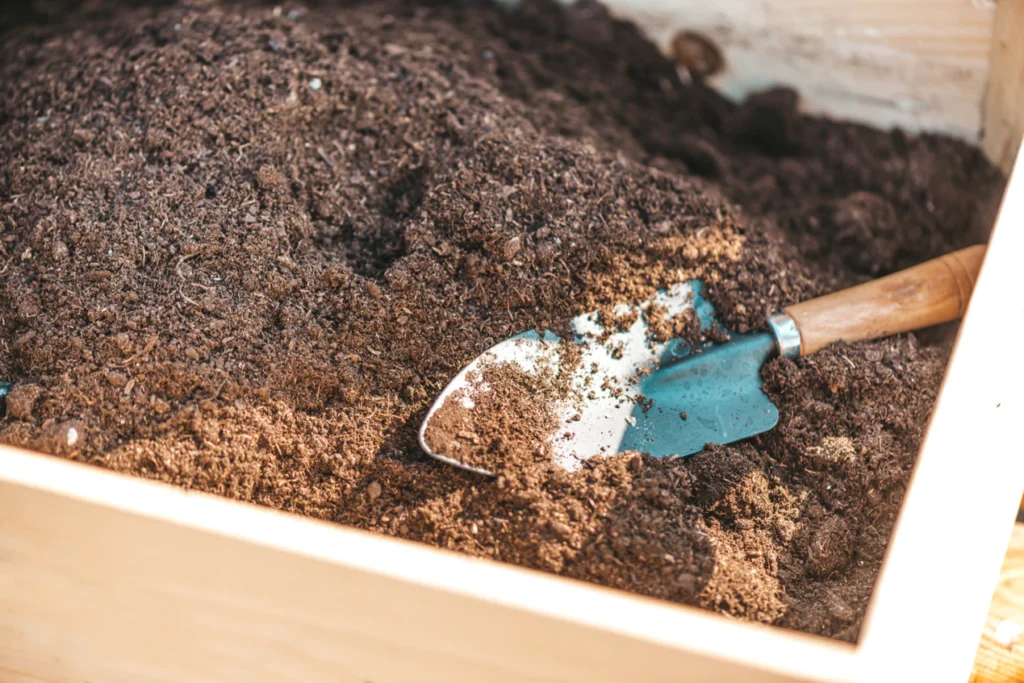 Garden soil in a raised bed with hand trowel